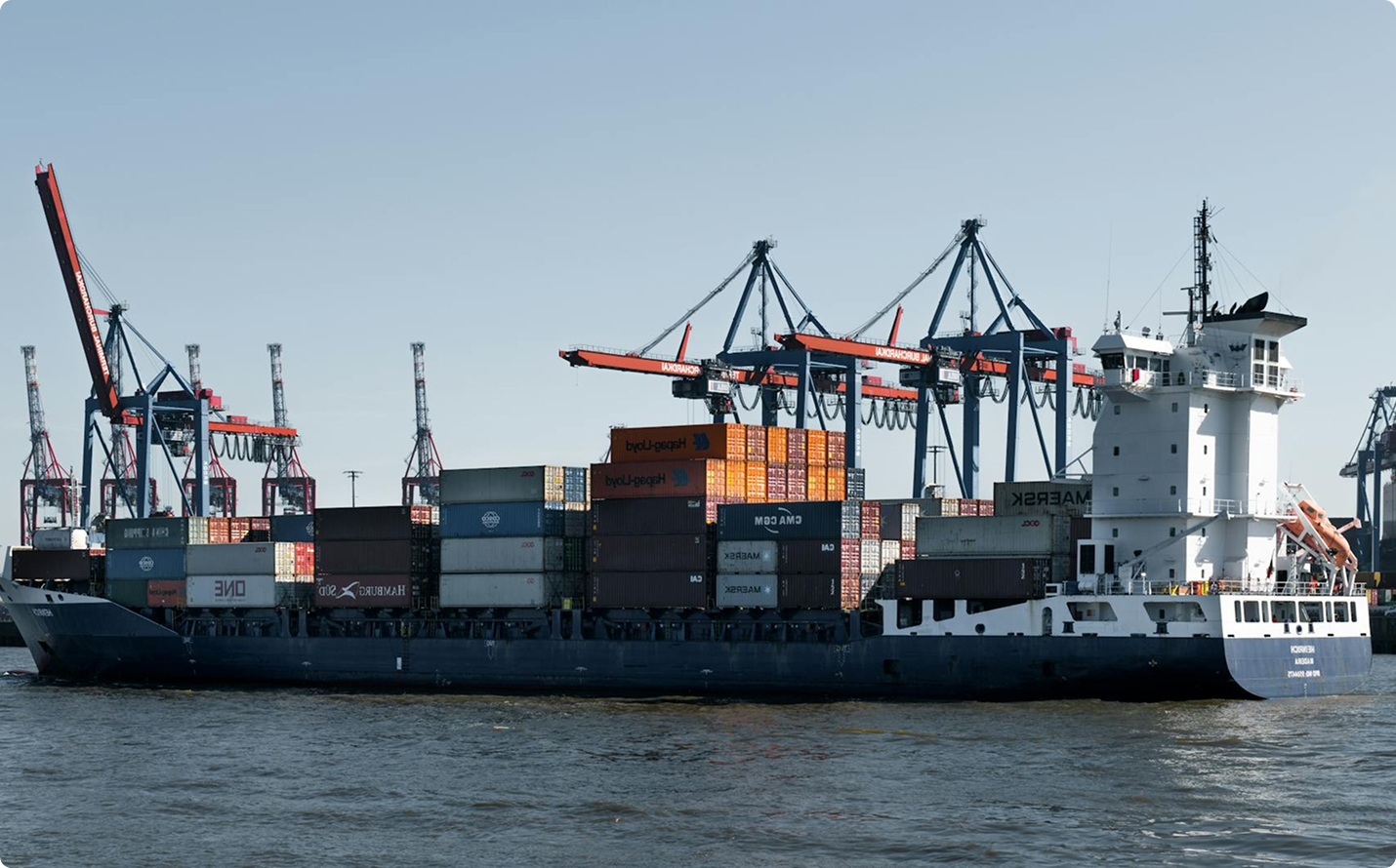 Port with cargo ships and shipping containers at dusk